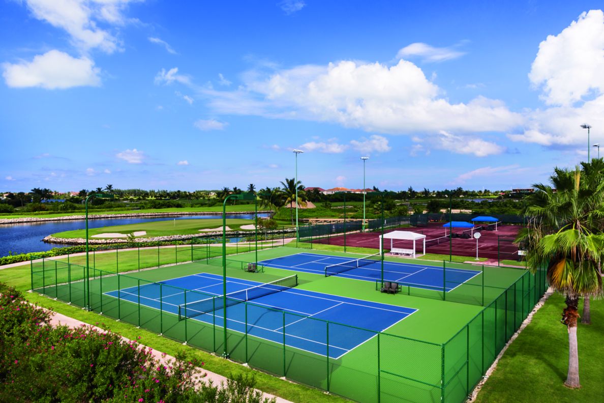 Aerial view of blue and red tennis courts surrounded by tall fencing