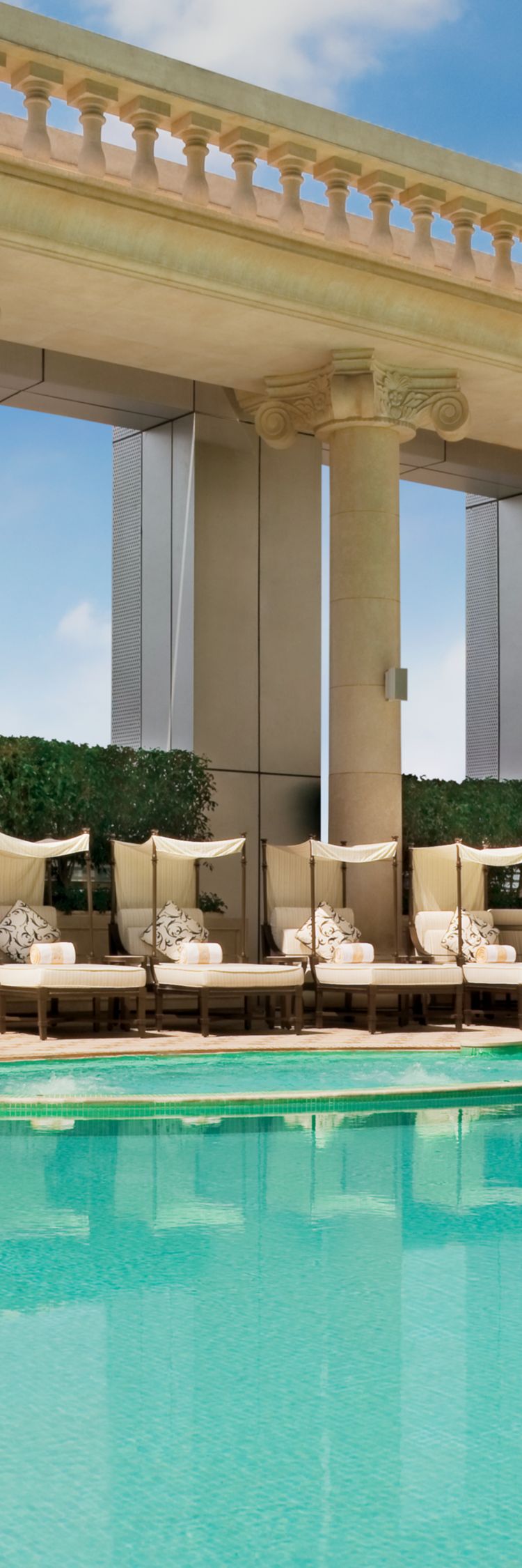 Shaded lounge chairs line a pool