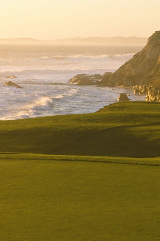 A flag indicates the 18th hole on a golf course, which sits next to the ocean 26. HalfMoonBay_00169