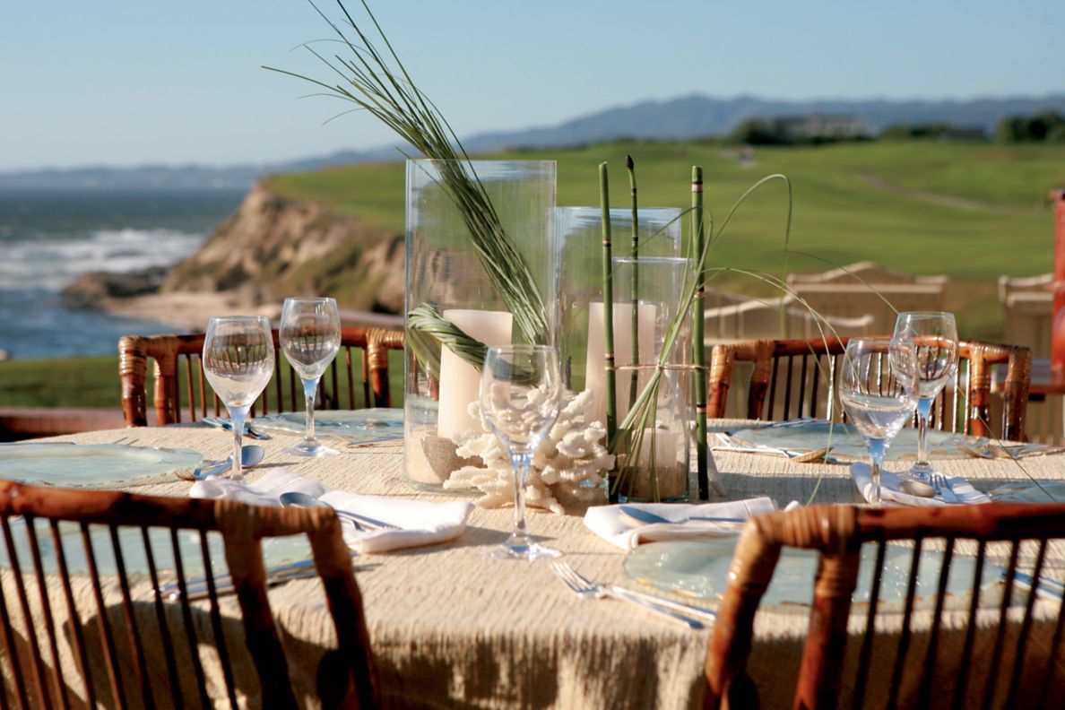 Table set for two on outdoor terrace with view of the ocean in the background. 