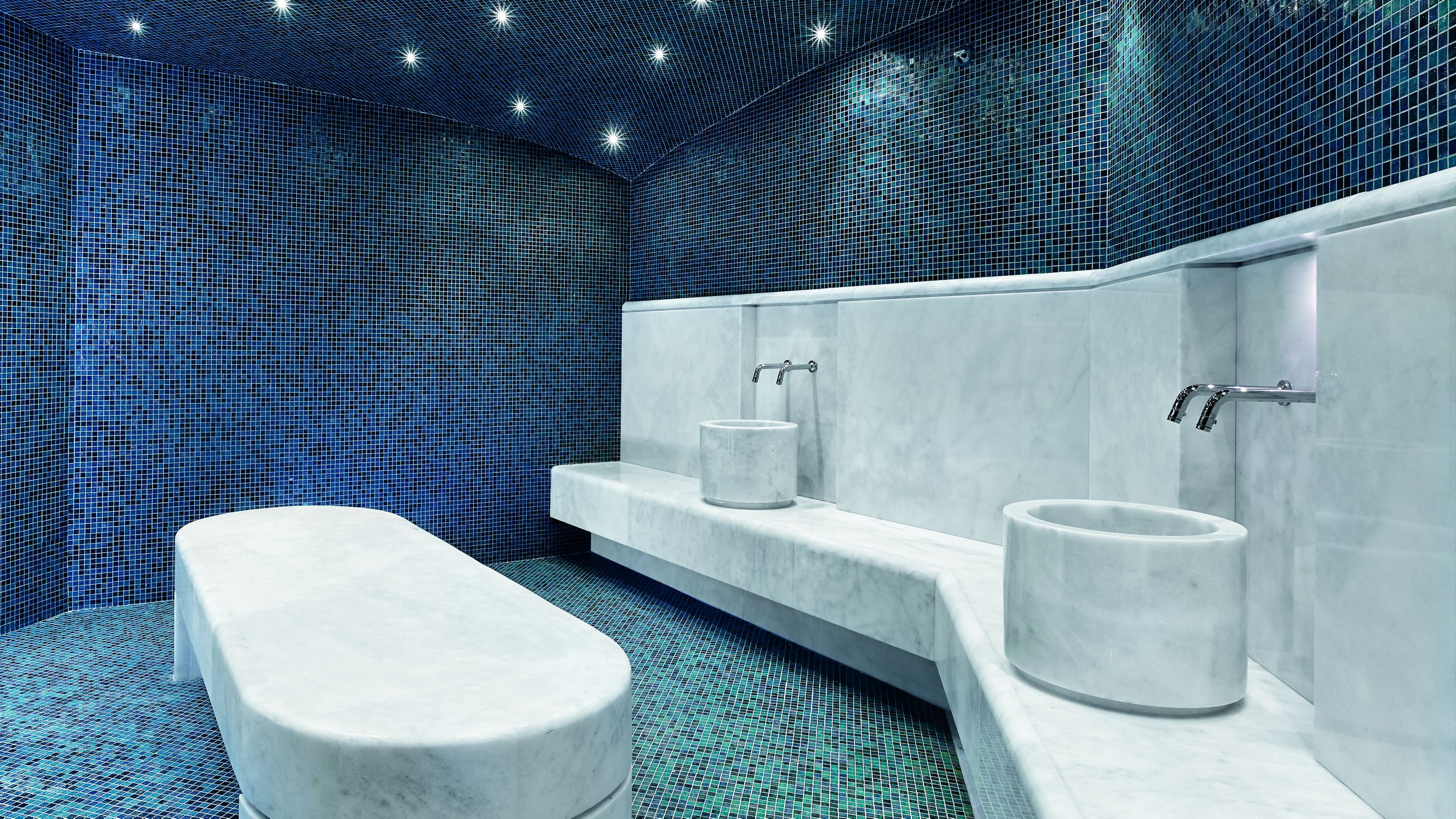 Turkish hammam with white marble fixtures and mosaic tile in blue and sea green