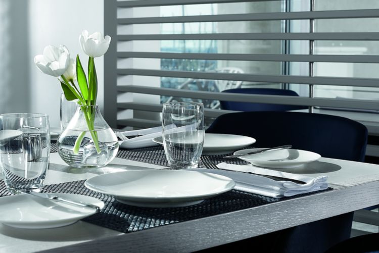 Table for four in shades of white and gray next to a white wall of slats