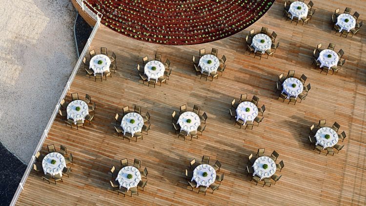 Aerial view of an outdoor event with round tables arranged in a semicircle