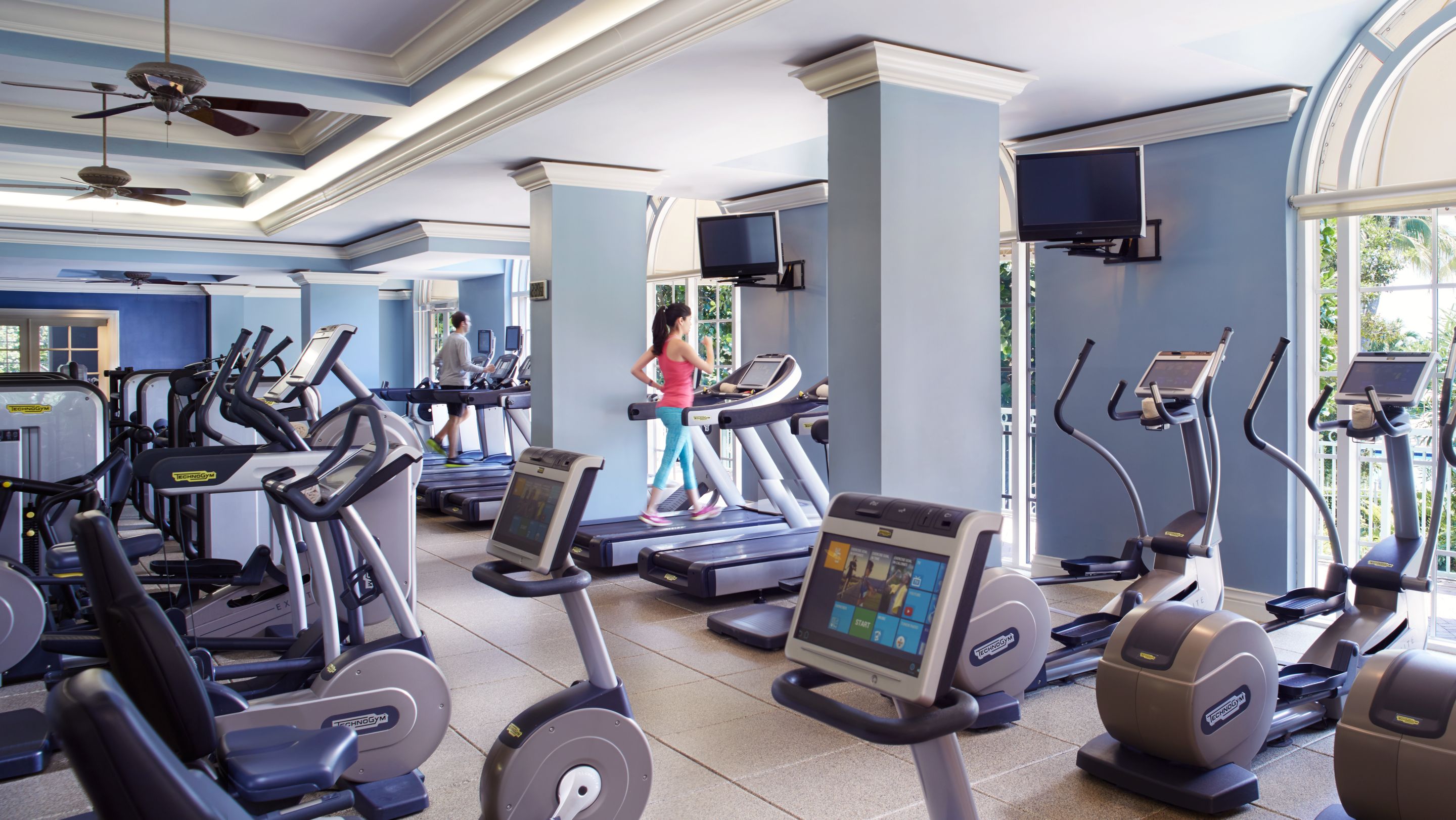 A woman on a treadmill in a large space with cardio machines