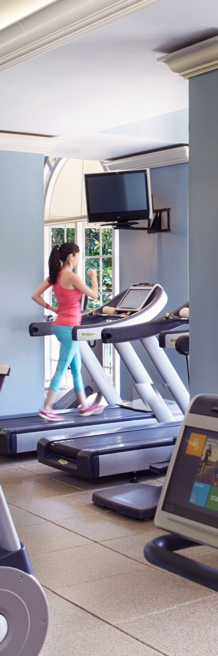 A woman on a treadmill in a large space with cardio machines