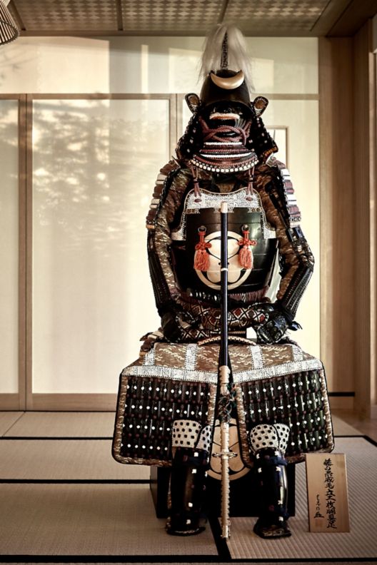Ancient samurai armor assembled in a spare, Japanese-style room with screen walls