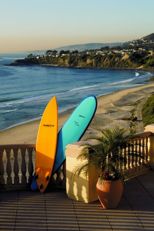 Surfboards propped up on the edge of the railing and overlooking the water and beach below