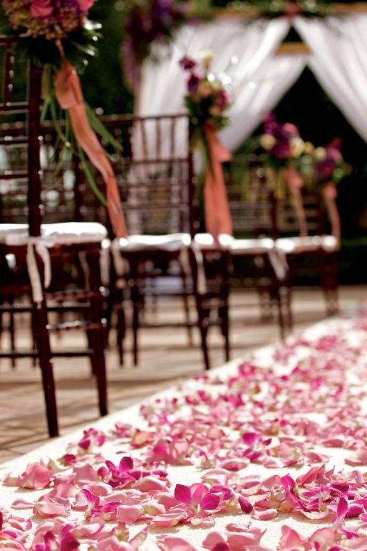Pink flower petals cover an outdoor wedding walkway.