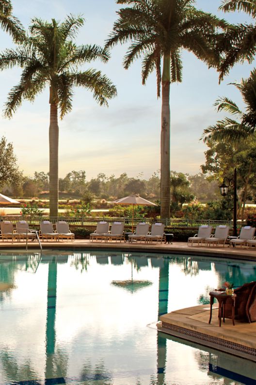 An expansive outdoor pool surrounded by plush lounge chairs and, beyond, the Tiburón Golf Course