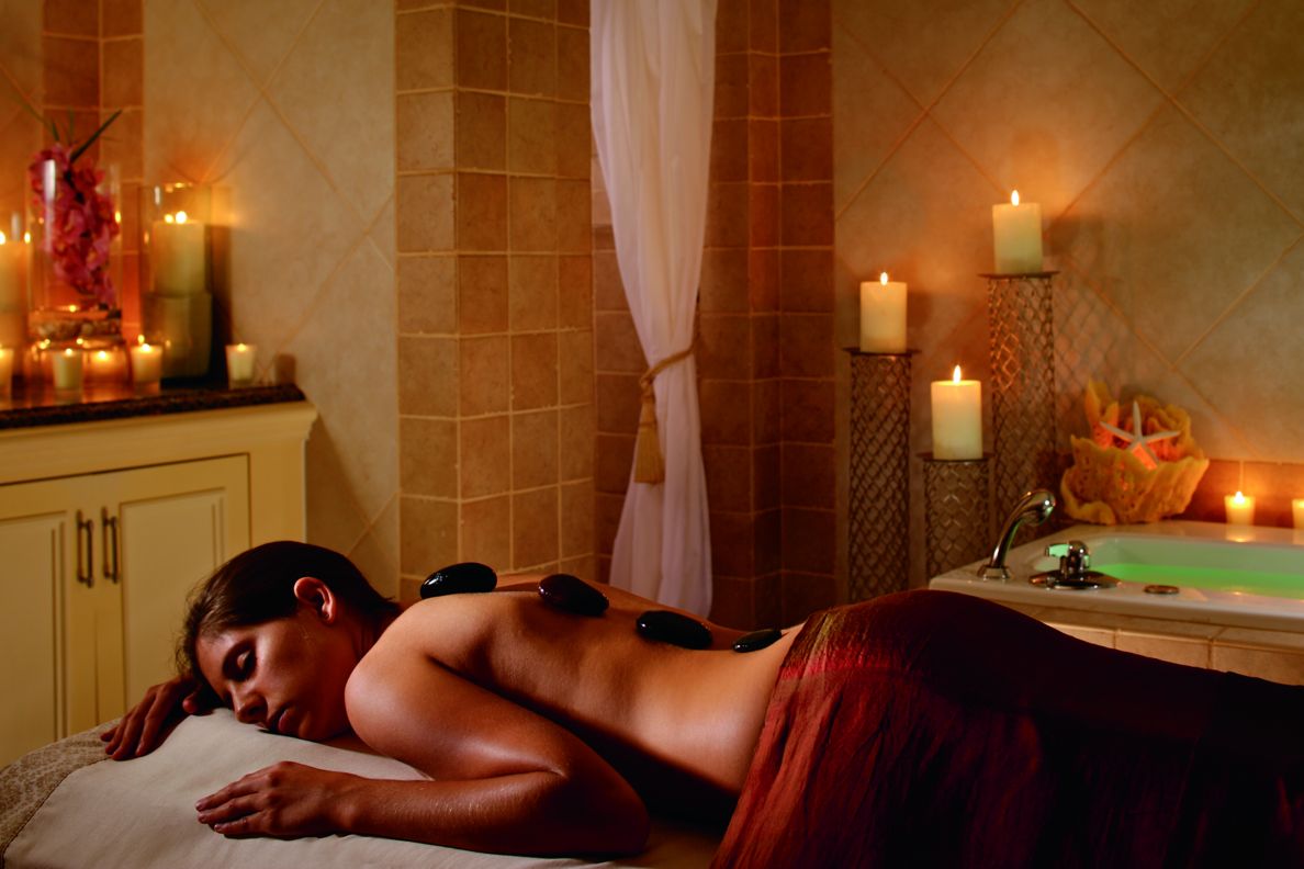 Someone lying down on a spa bed in a candle lit spa room.