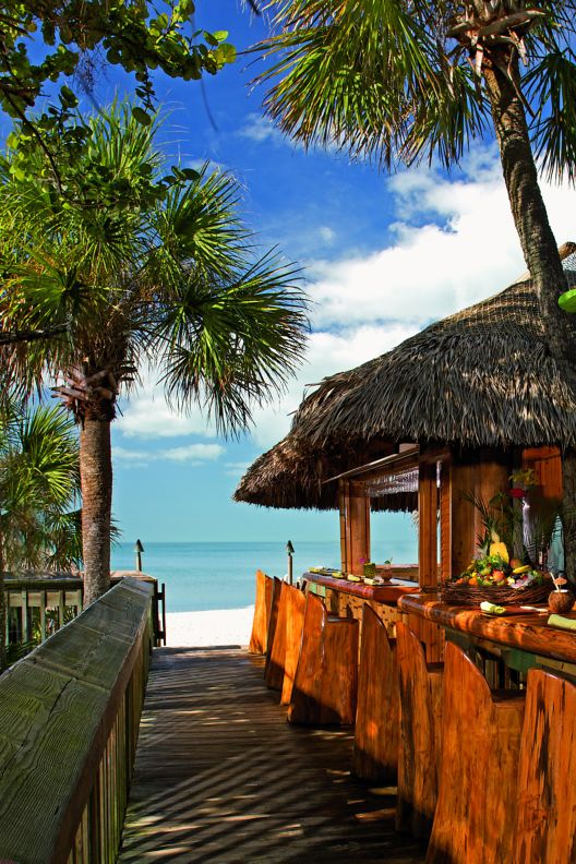 An outdoor bar leads up to the palapa that houses Sand Bar, with the ocean just beyond