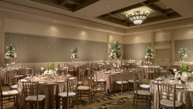 Reception with roundtables, champagne-colored tablecloths and tall green-and-white floral centerpieces