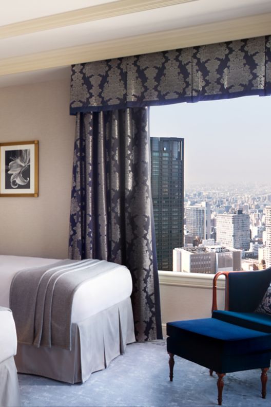 Two beds in the executive suite with a lounge chair and view of the city.