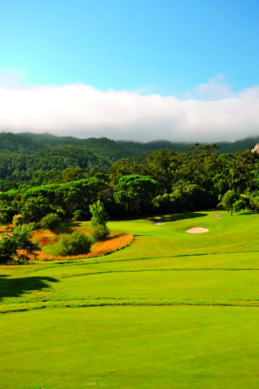 Golf course with rolling hills and background of mountains. 