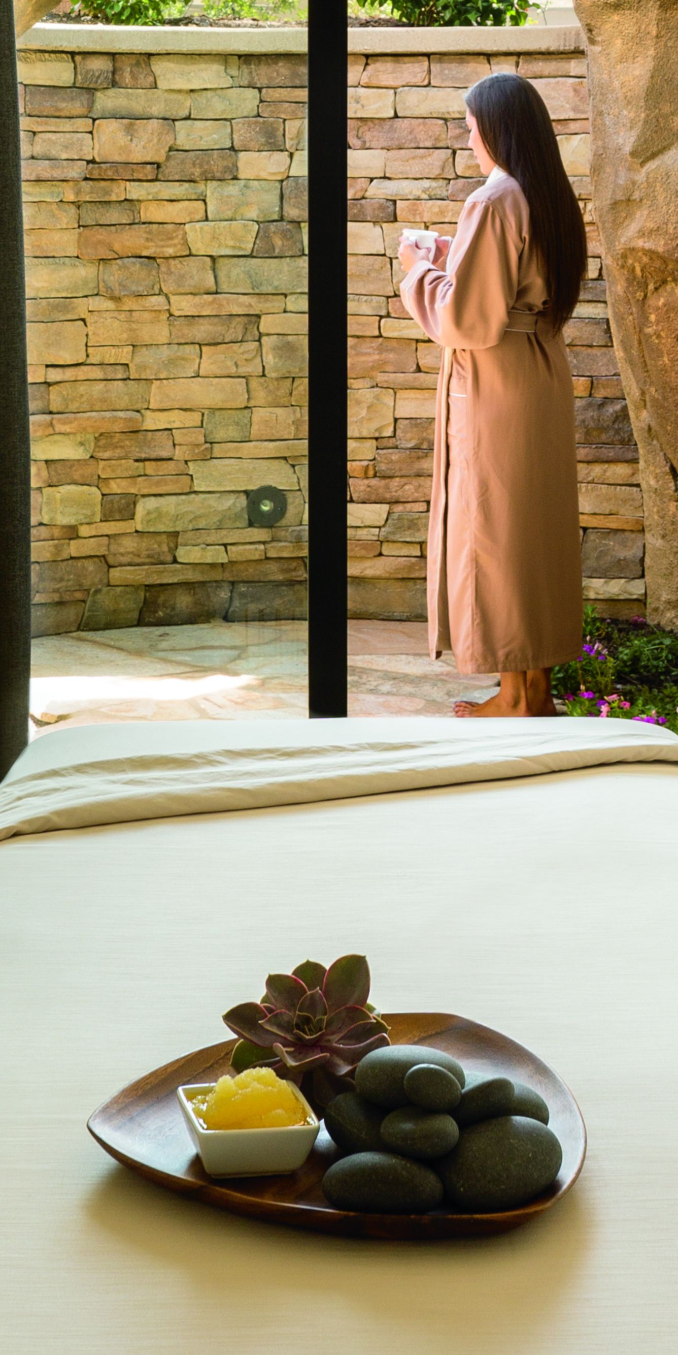A robed woman stands on the patio of a spa treatment room