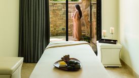 A robed woman stands on the patio of a spa treatment room