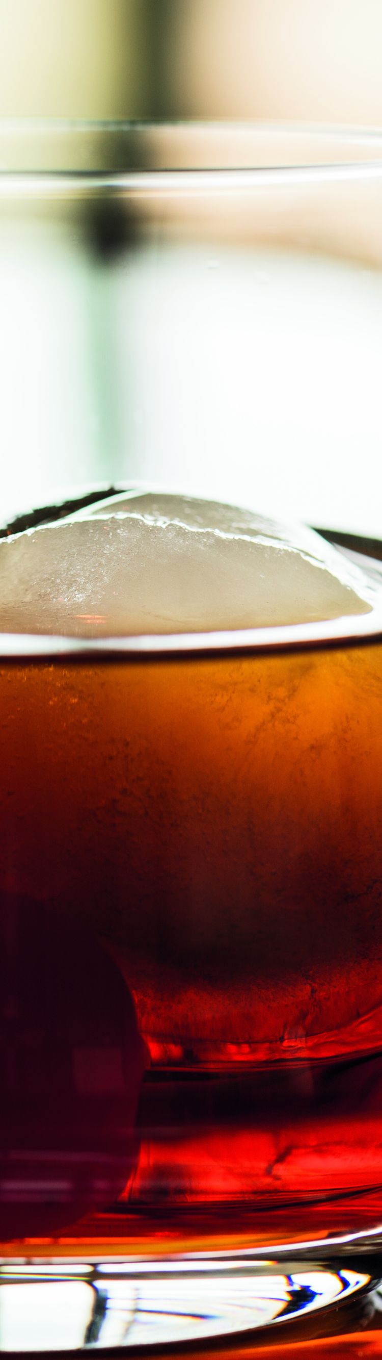 A cocktail with an ice cube and cherry