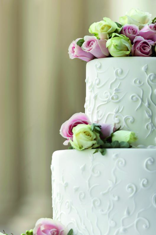 Two-tier wedding cake garnished with white and lavender roses