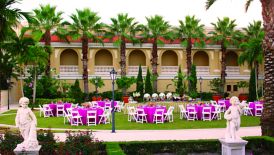 Tables and chairs set up on a lawn overlooked by palm trees and the resort