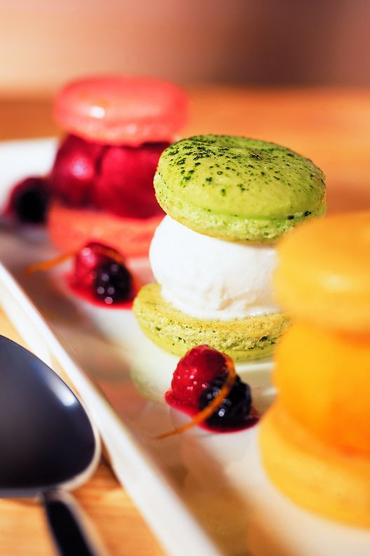 Three macaroons on a tray with a silver spoon. 