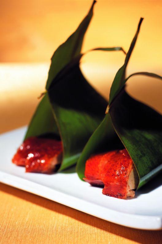 Appetizer wrapped in a green leaf on a tray. 