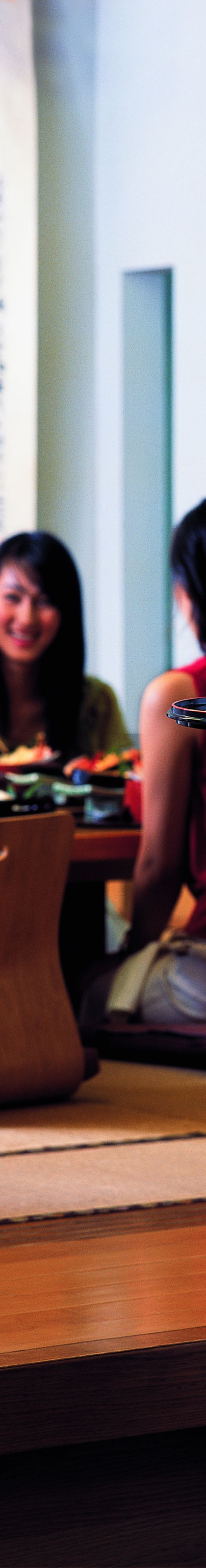 Group sitting on floor in front of a table in dining area of a restaurant. 