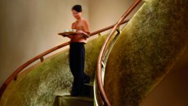 Woman holding a tray and walking down a curved staircase
