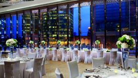Wedding reception in a large space with tall ceilings, floor-to-ceiling windows and green-and-white florals