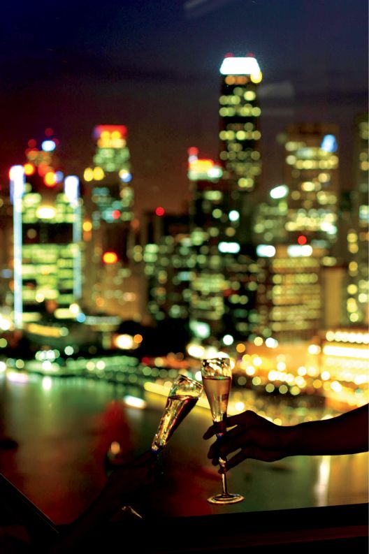 Two people toasting with the city skyline in the backdrop.