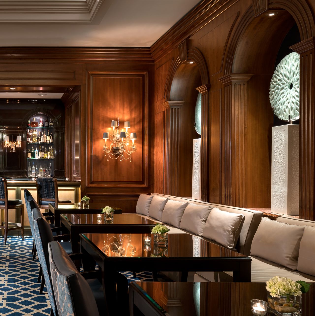 Banquettes, dining tables and a bar in a room with patterned carpeting and wood-paneled walls