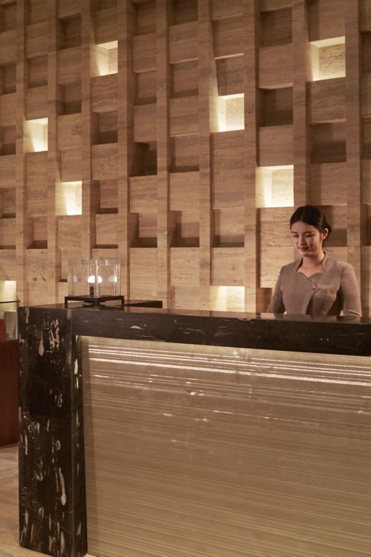 The entrance of a spa with an employee at the reception desk.