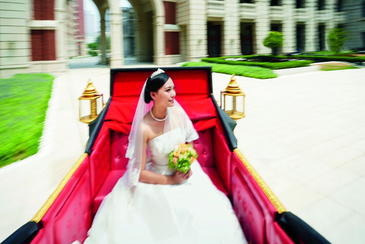 Bride in a carriage in her wedding dress heading to the hotel.