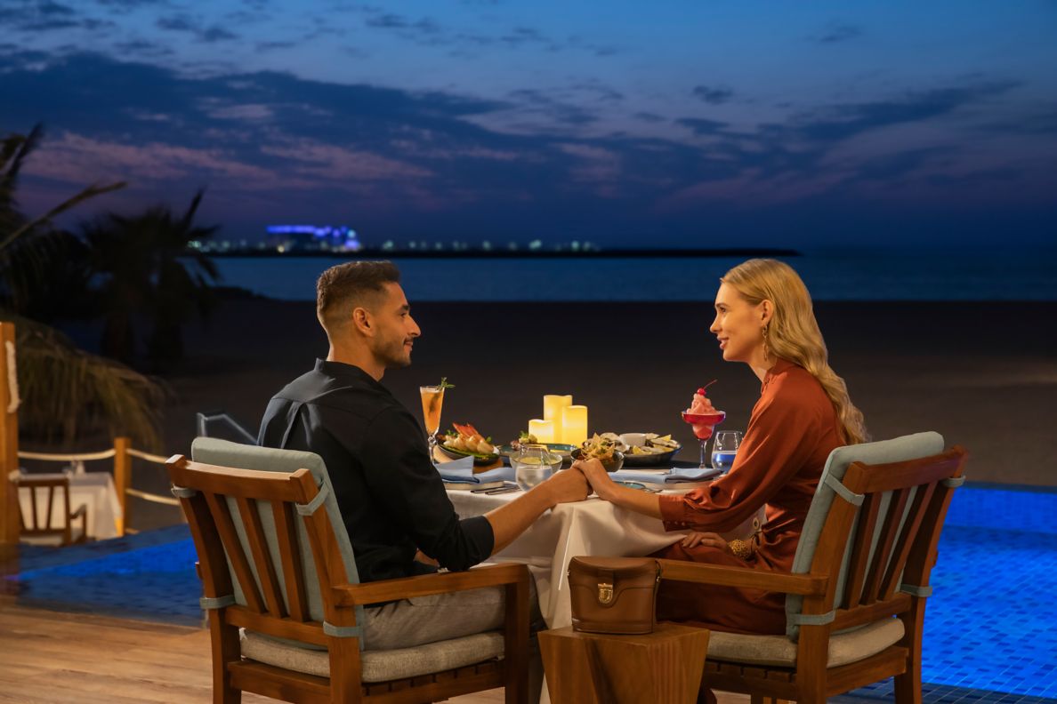 A couple sitting and eating on the beach in a private cabana. 