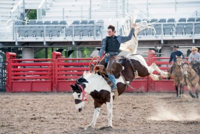 A cowboy rides a horse at the rodeo