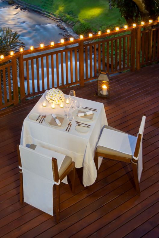 Romantic dinner setup next to the river with white table cloth and flowers.