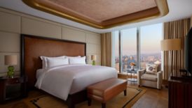 A hotel suite bedroom with a city view