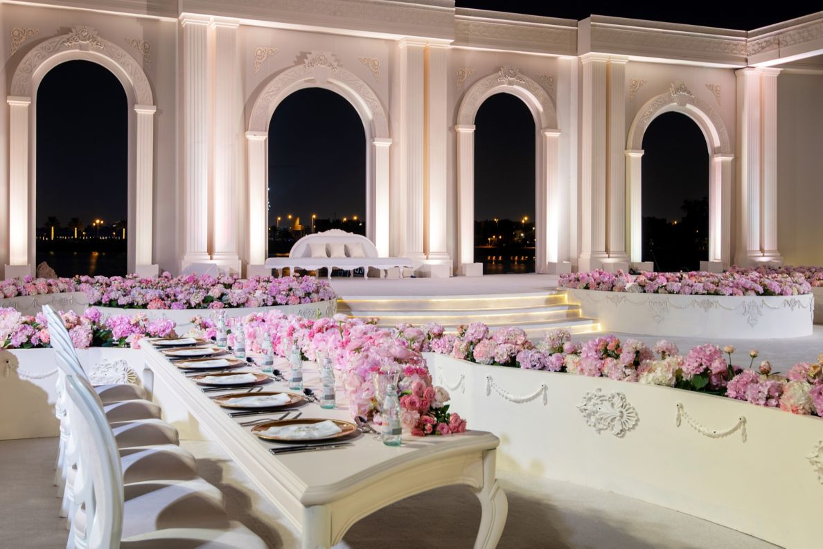 An outdoor wedding area with many pink flowers.