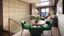 A dining area in a yacht's cabin with green chairs
