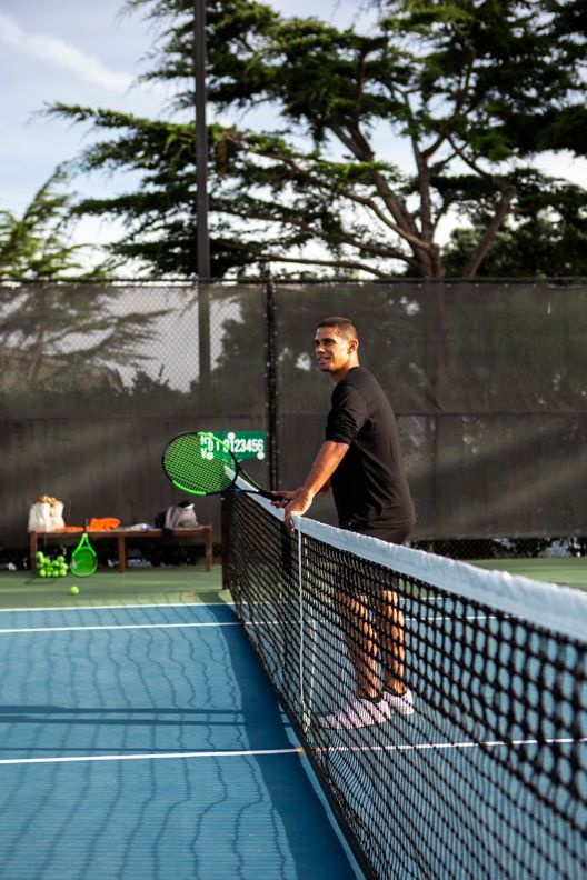 Man leaning on tennis net.