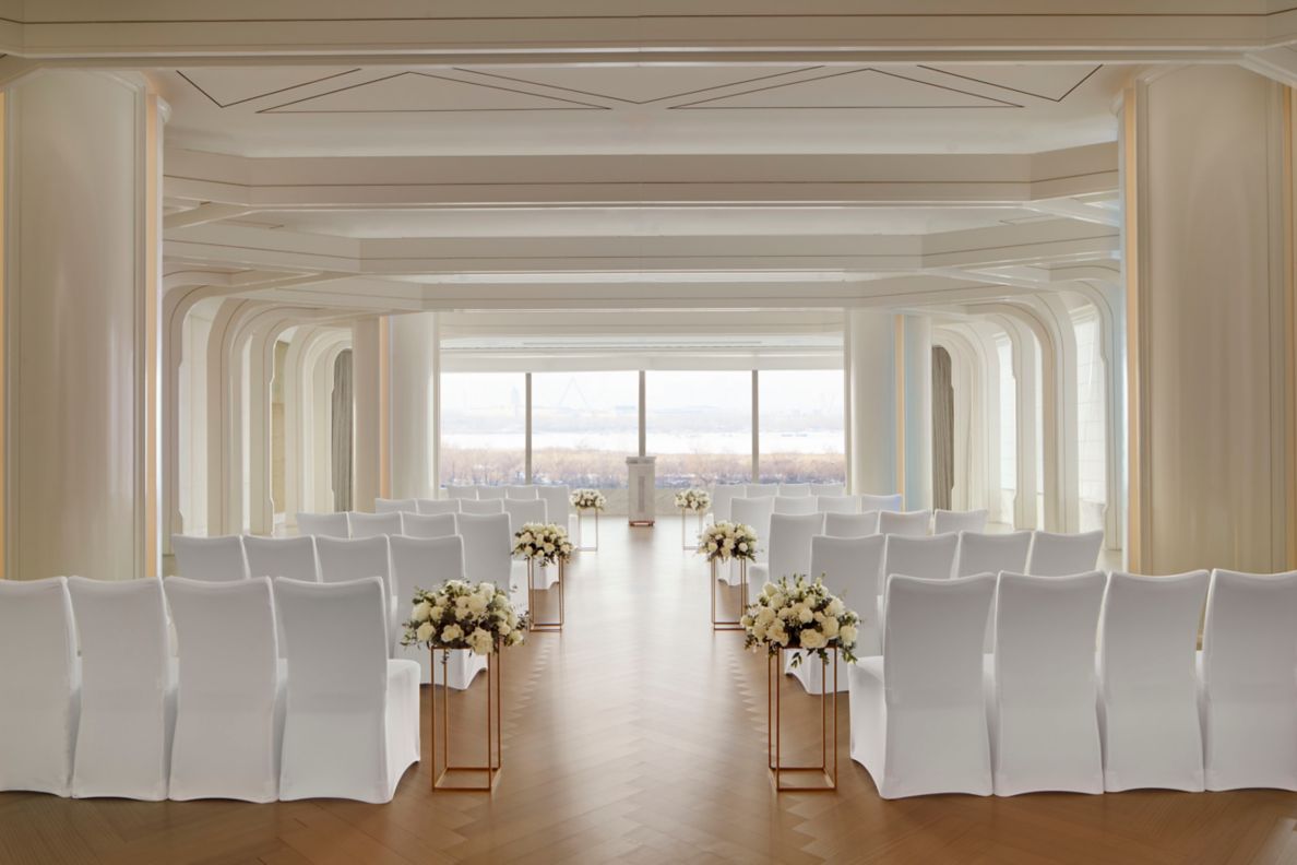 A private room set up for a wedding with covered chairs facing the windows.