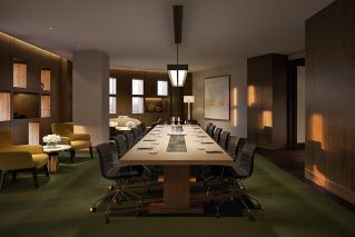 Boardroom with green carpet and yellow arm chairs.