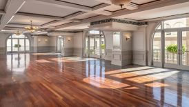 An empty ballroom with hardwood floors, and window