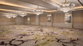 An empty ballroom with floral carpeted  floors, an