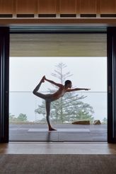 Woman doing yoga by a window overlooking a lake