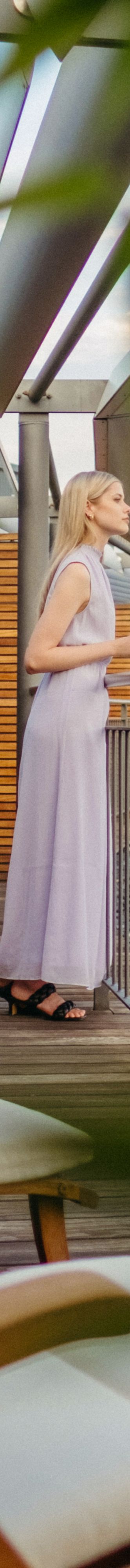 A woman stands on a tree-shaded balcony
