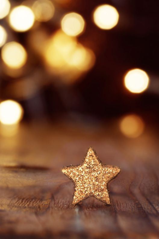 Little gold star on wood table with festive lights