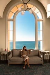 Woman on cozy couch with ocean view in the backgro