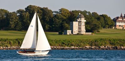 Sailboat on water with lighthouse in background.