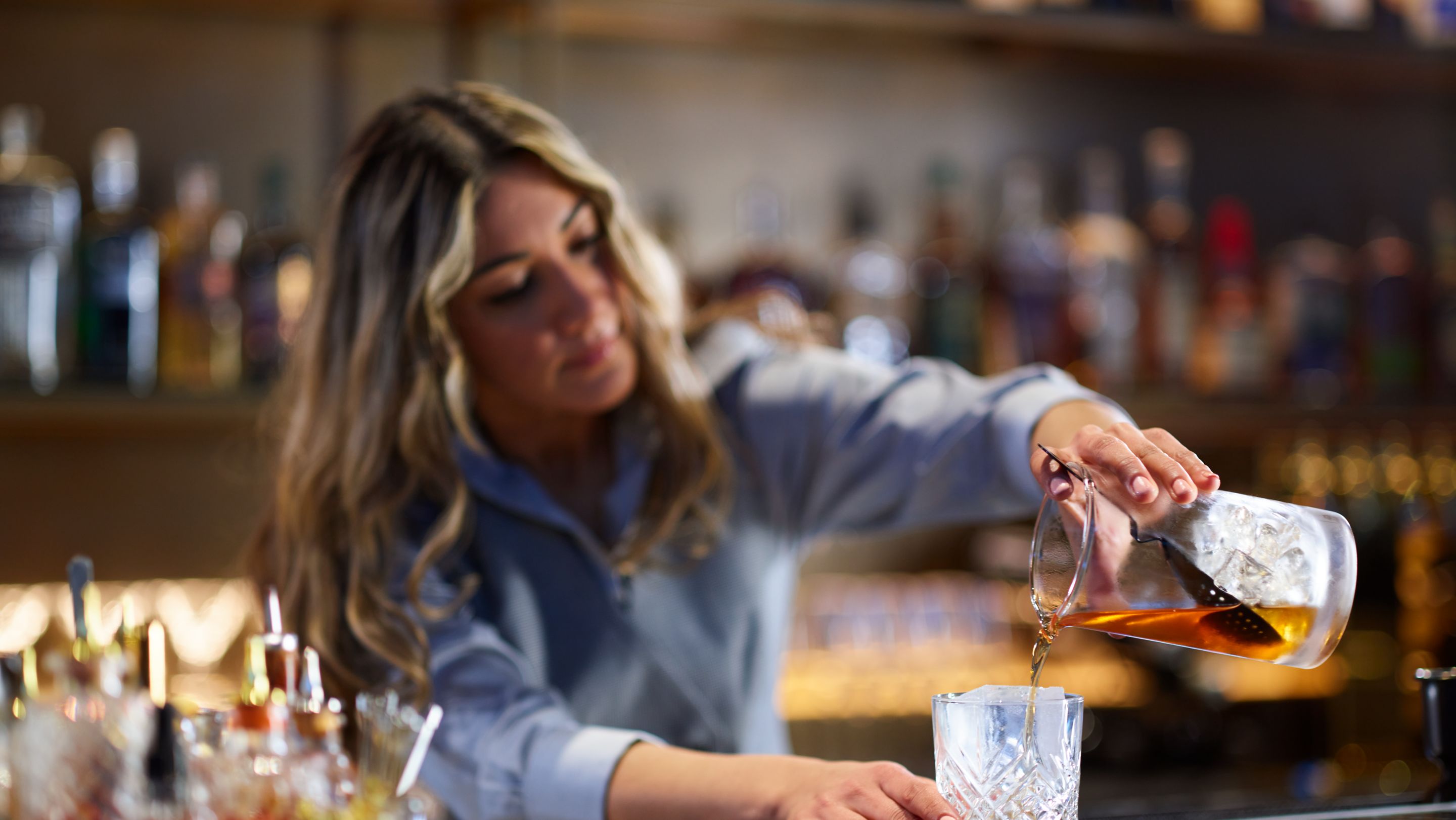 A bartender pouring a drink behind a bar.