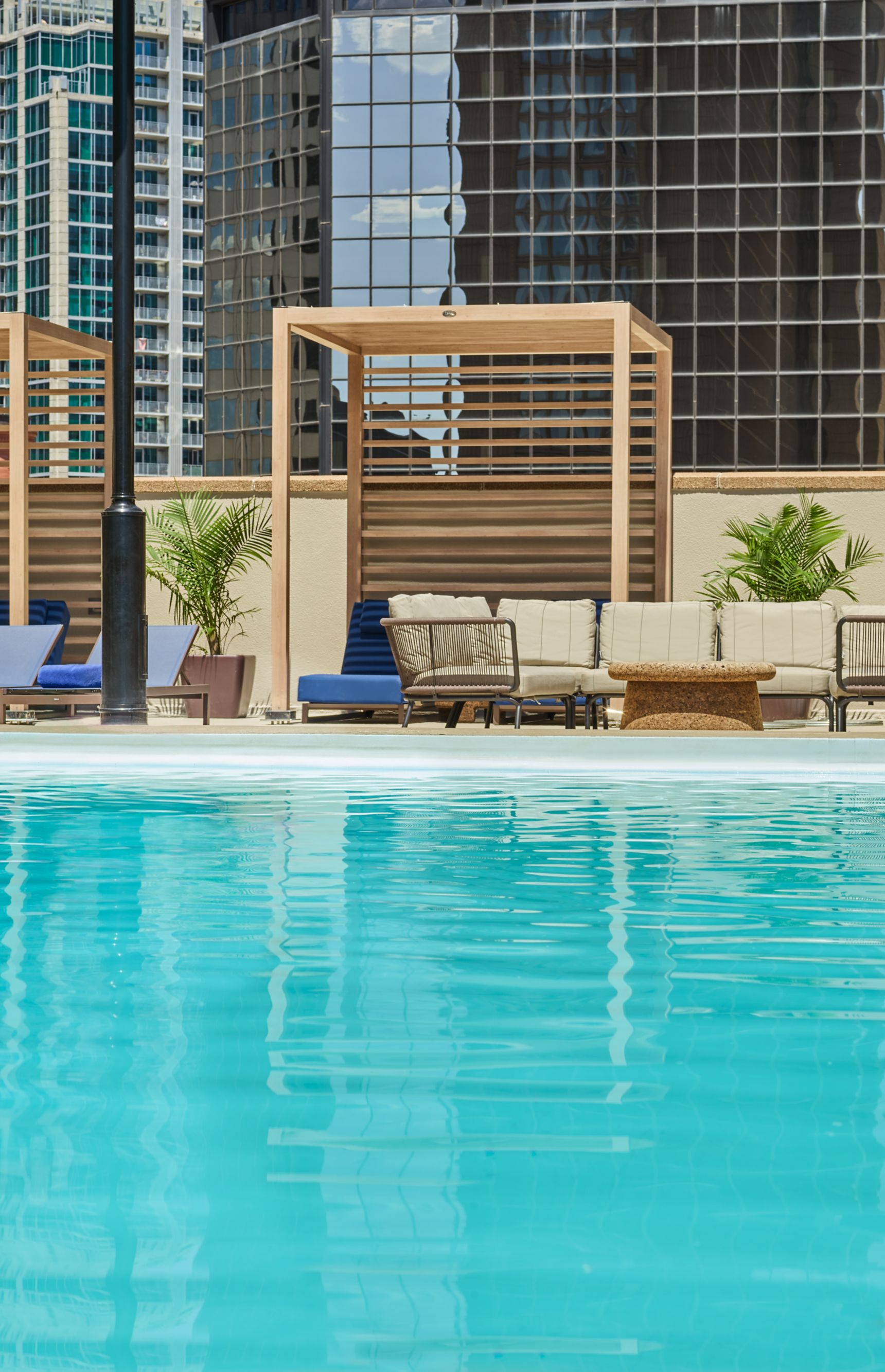 Outdoor pool with cabanas and chairs on the side.